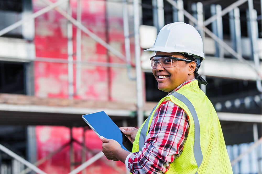 female construction worker holding a tablet and smiling